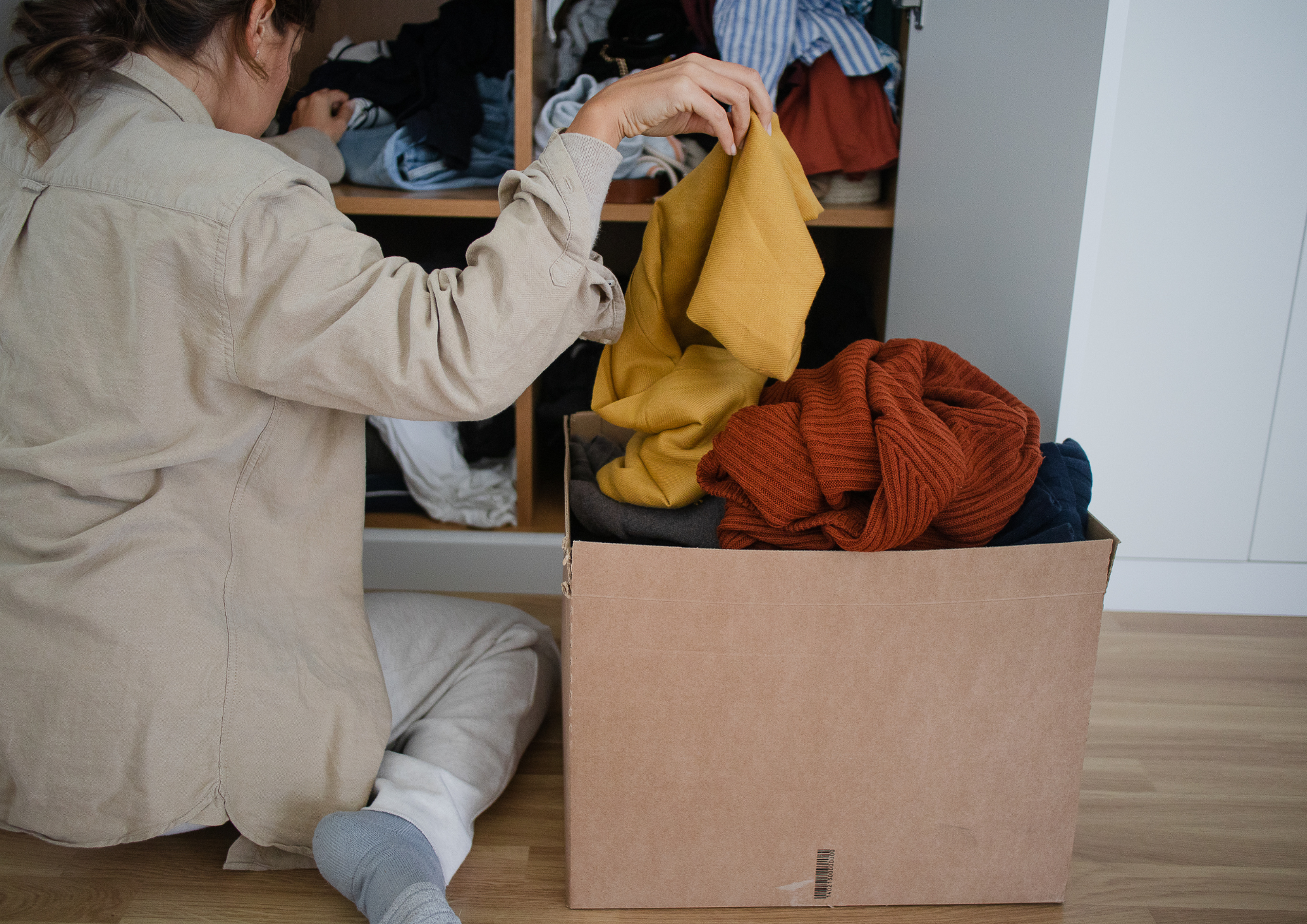 Woman decluttering clothes into a donation box